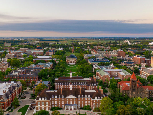 Aerial view of Urbana Champaign Campus, with a pink sunset in the background